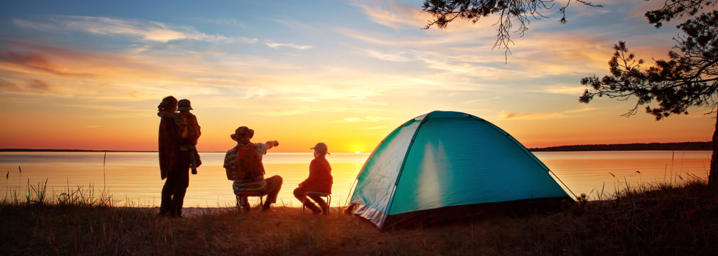 Family of four camping at sunset