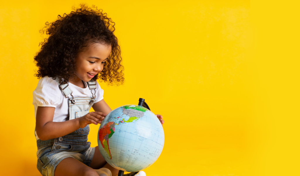 Child holding globe on yellow background