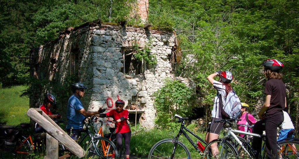People on bikes examining a crumbling stone house
