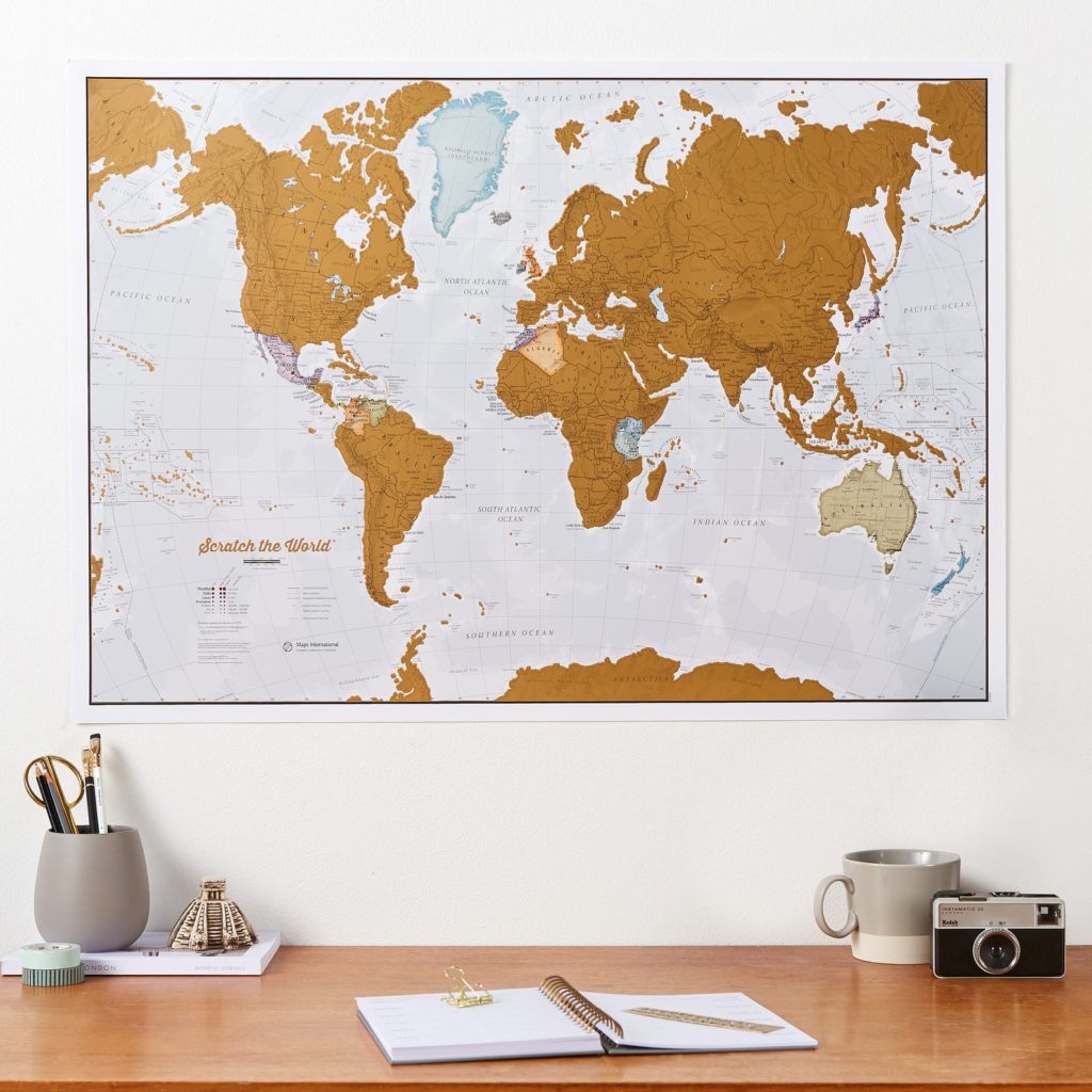 Scratch-off world map hanging on wall above a desk