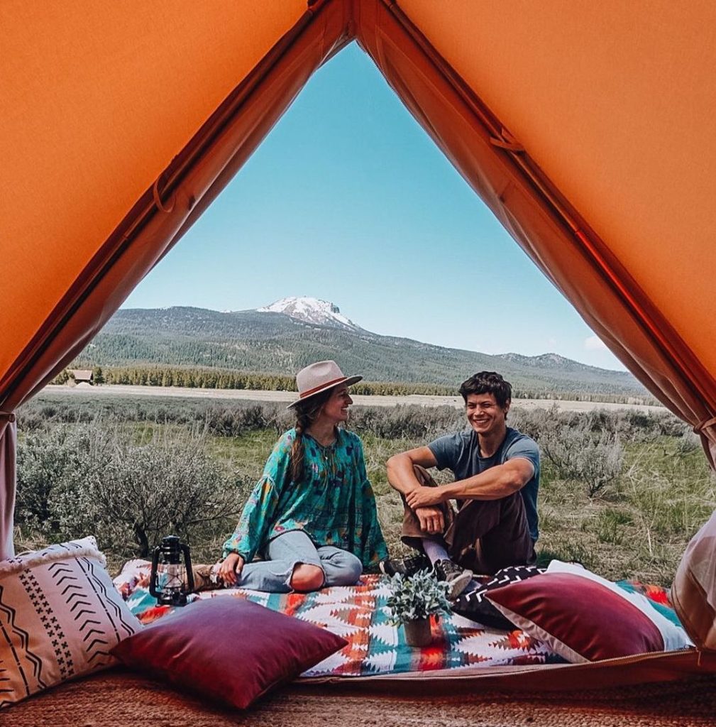Two people sitting at the opening of a glamping tent at Wander Camp in Montana