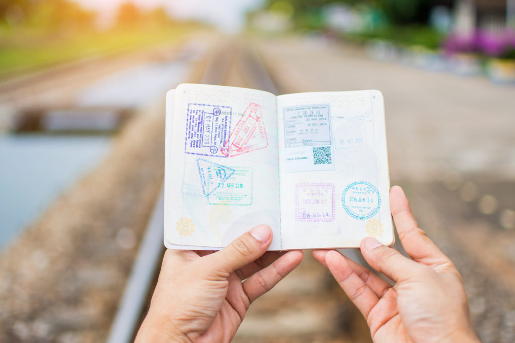 Hands holding a passport open to pages full of stamps