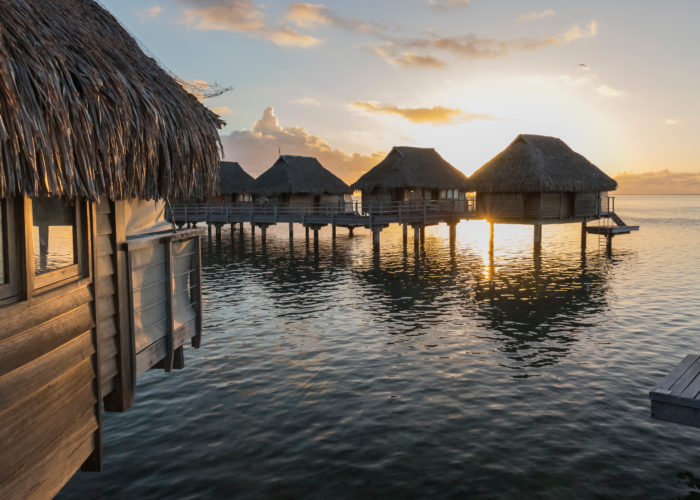 Line of overwater bungalows at sunset