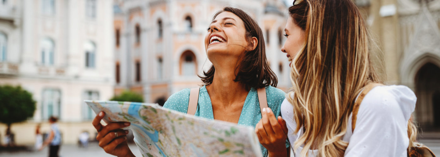 Two women laughing a reading a map in a European city