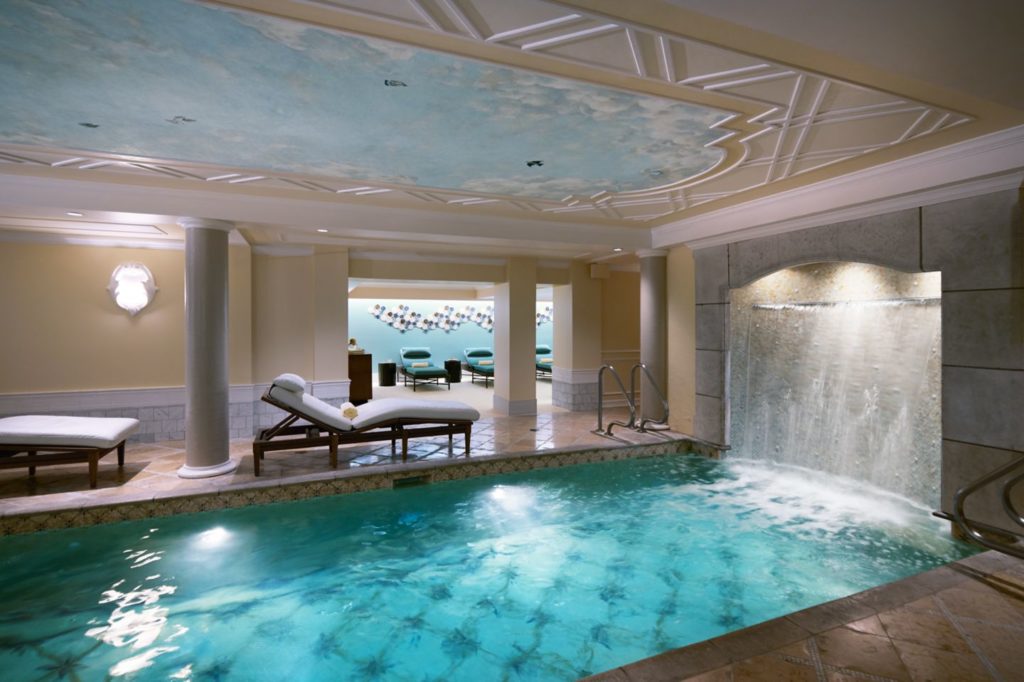 Pool and waterfall surrounded by lounge chairs at the Kohler Waters Spa