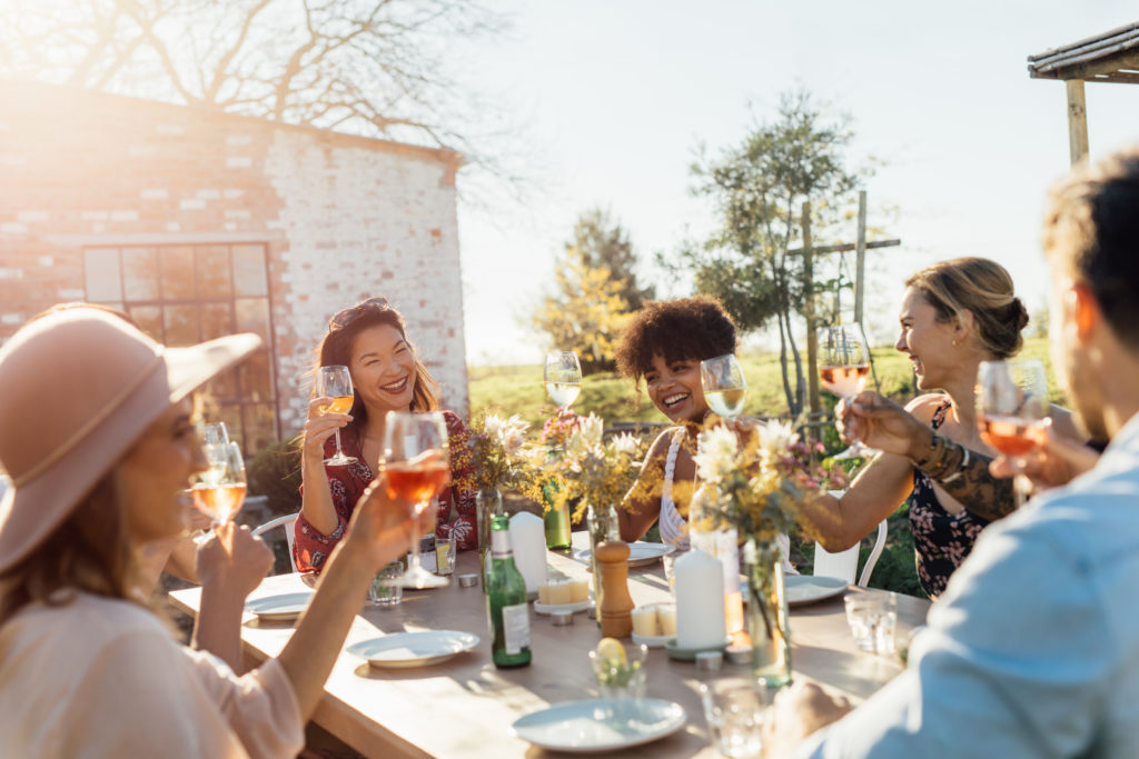 Group of friends toasting with wine glasses at outdoor dining table