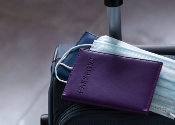 Purple suitcase with masks and passport on top