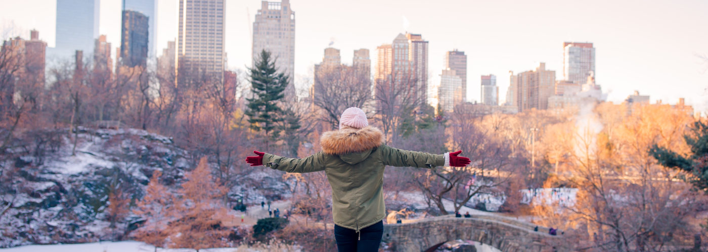 Woman gesturing with wide arms to a snow covered Central Park