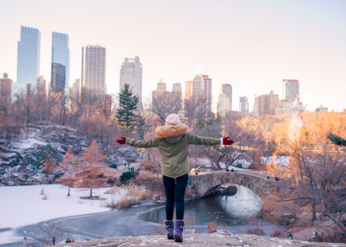 Woman gesturing with wide arms to a snow covered Central Park