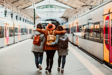 Three friends facing away from camera at train station