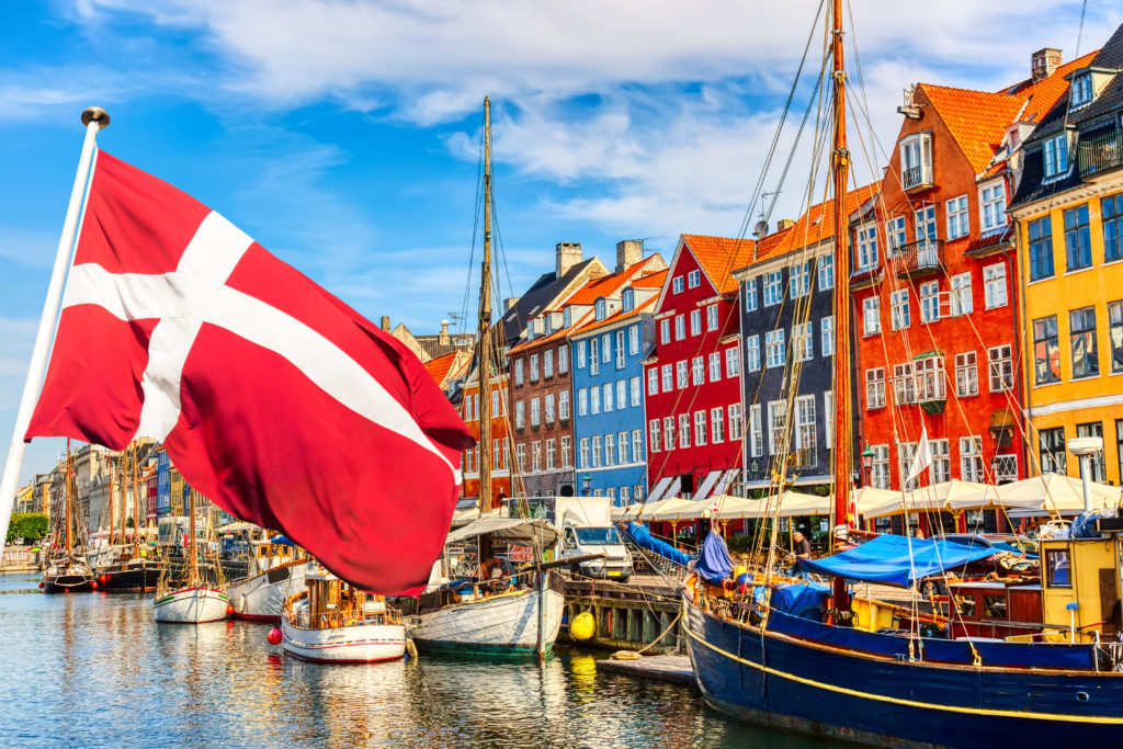 Old Nyhavn port in the center of Copenhagen with Denmark flag in the foreground