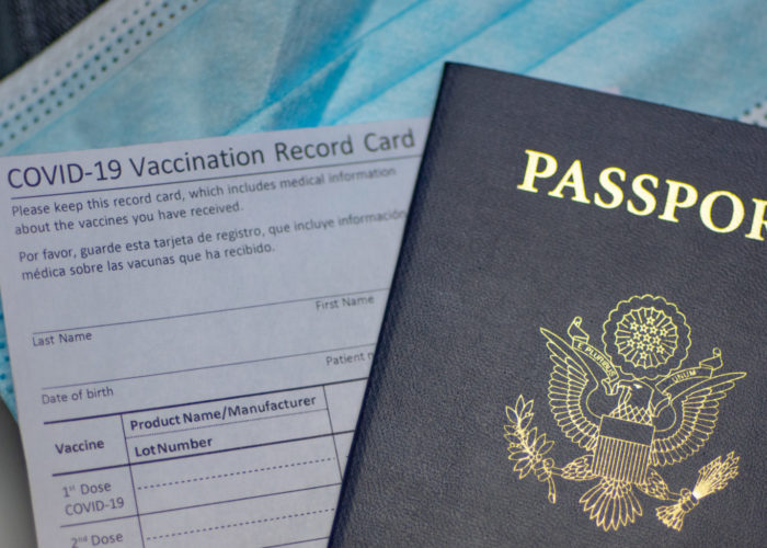 Passport, face mask, and vaccine card on table