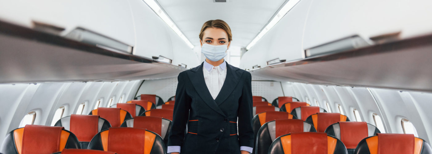 Flight attendant standing in the center aisle of a plane cabin