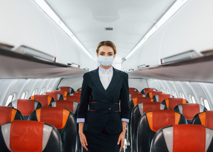 Flight attendant standing in the center aisle of a plane cabin