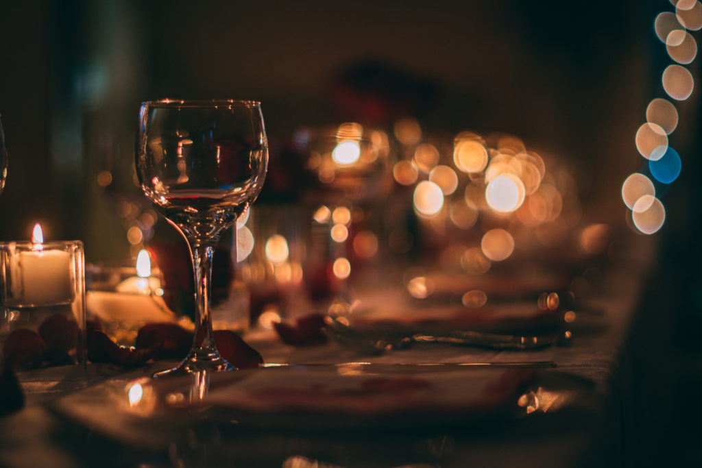 Romantic table setting in low light with wine glass in the foreground
