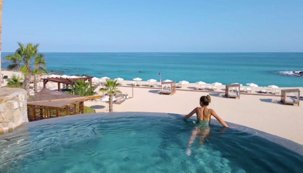 Woman in pool overlooking the beach at Hilton Los Cabos Golf & Beach Resort