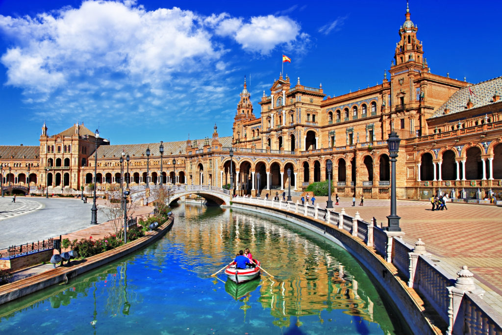 People rowing a boat down a canal in Sevilla, Spain