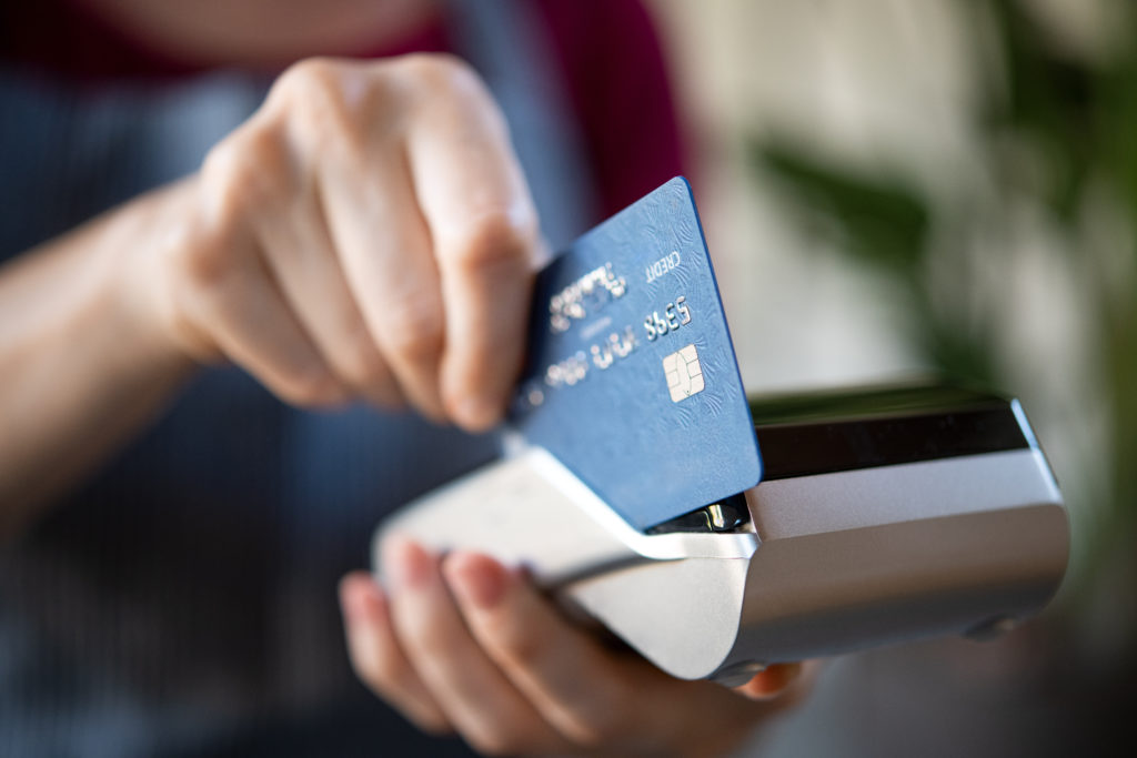 Close up of hand swiping a credit card in a credit card machine