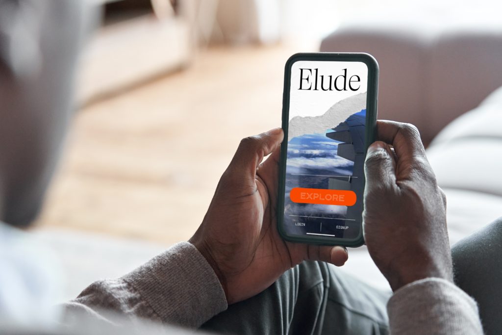 A man holding a phone showing the app Elude
