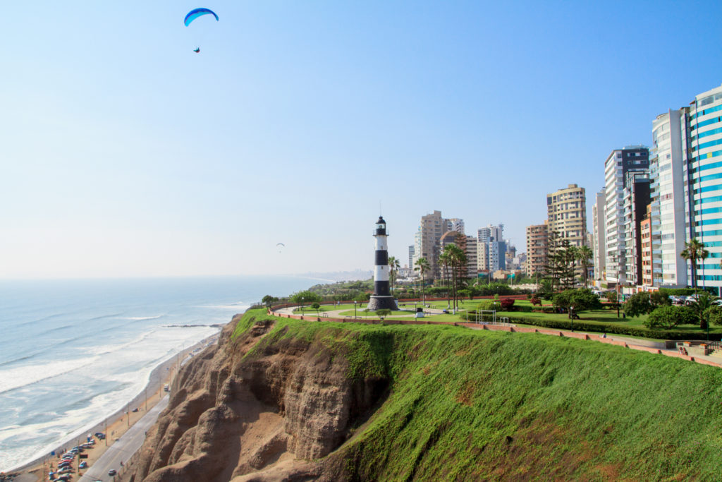 Paraglider over a lighthouse at the edge of the city in Peru