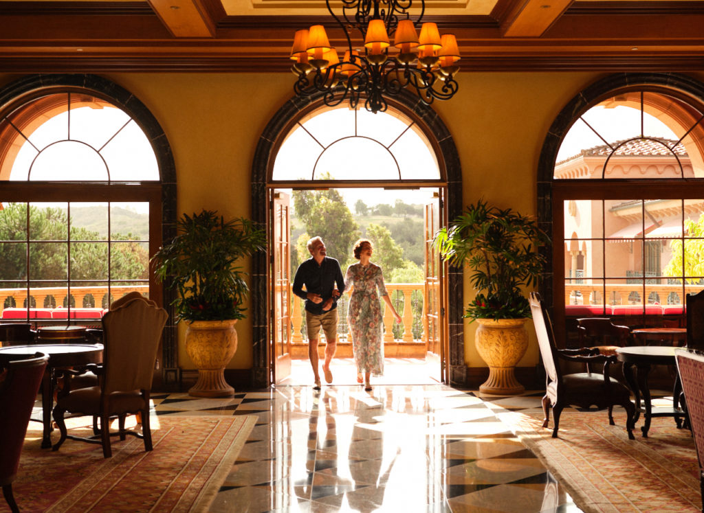 A couple walking into a spacious dining area with three large arched windows at the Fairmont Grand Del Mar