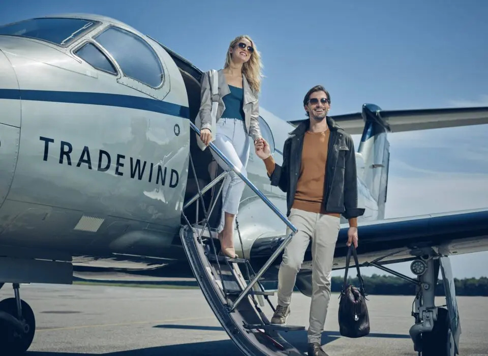 A man and woman disembarking a semi-private jet operated by Tradewind