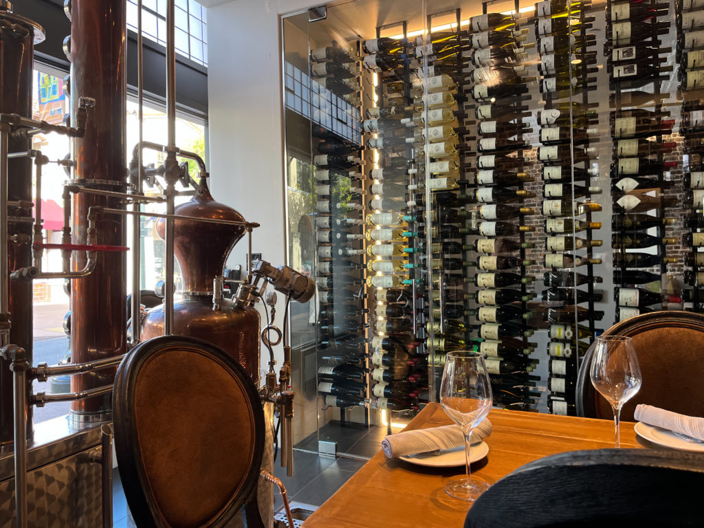 Still and wall of wine in The Distillery dining room at Hotel Cerro in San Luis Obispo, California