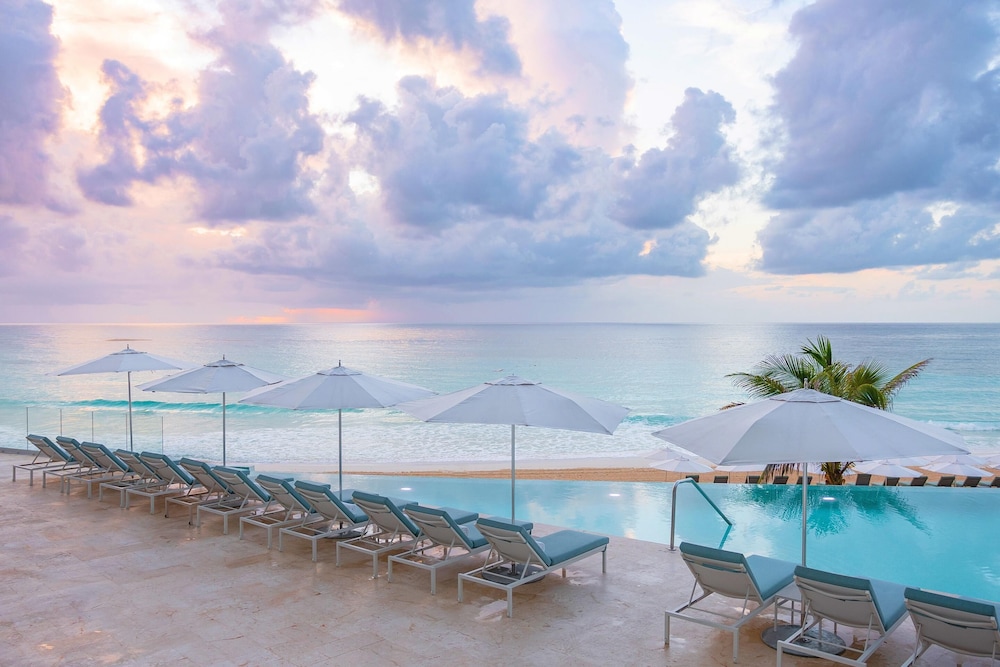 Outdoor lounge area by the pool and ocean at dusk at Sun Palace Couples Only All-Inclusive, Cancún, Mexico