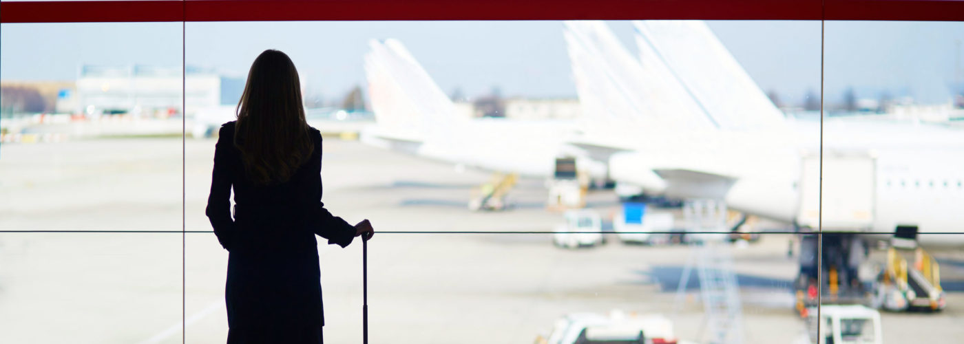 Woman looking out of airport window at planes on runway