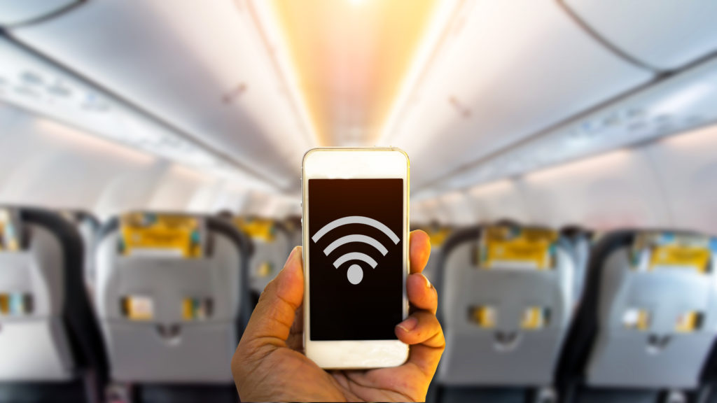 Person holding up smartphone displaying the WiFi symbol in an empty plane cabin