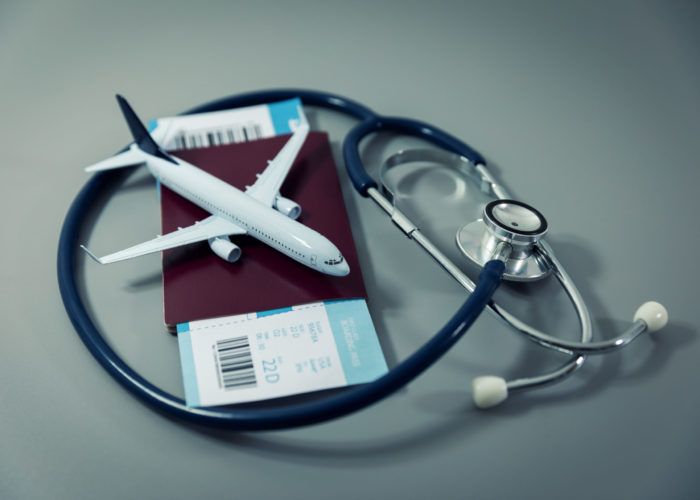 Stethoscope and model airplane resting on top of a passport and set of boarding passes