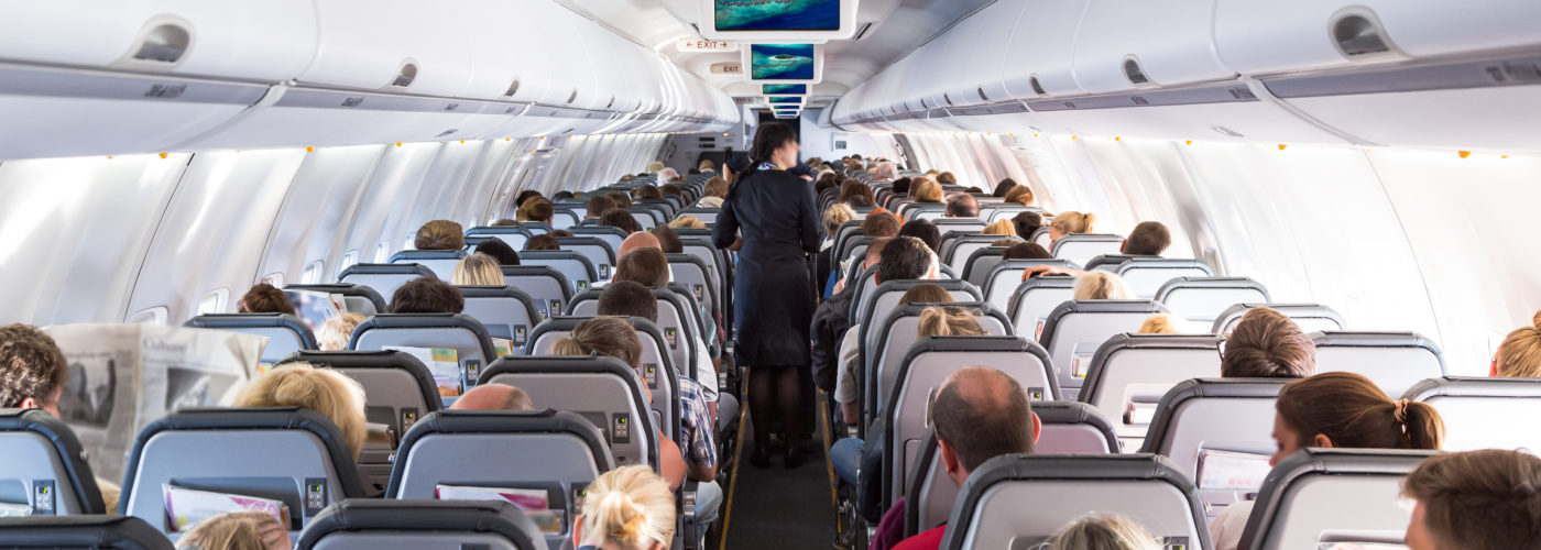 Flight full of people with flight attendant in aisle