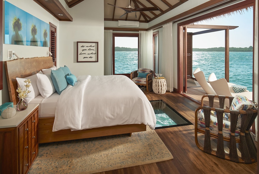Bedroom overlooking the water through large glass windows at Sandals South Coast, Jamaica