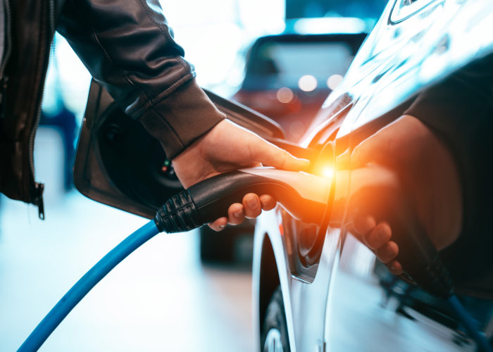 Close up of hand plugging in an electric car