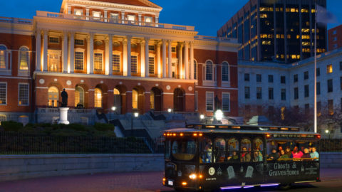 Trolley of the Doomed Boston Ghost Tour bus riding past historic buildings