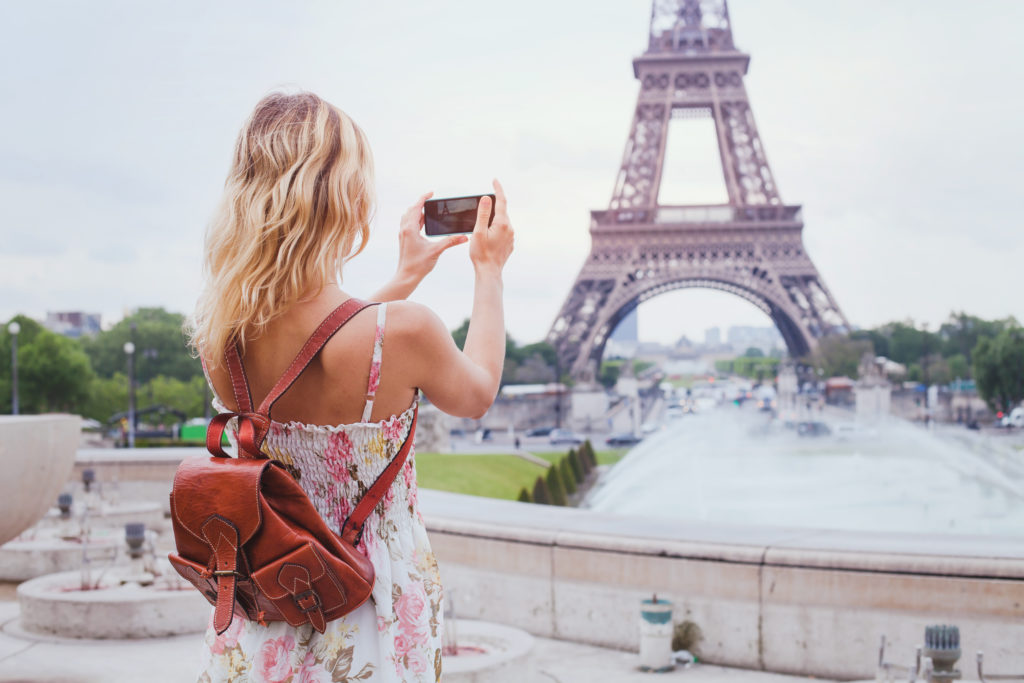 Woman taking a photo of the Eiffel Tower on her smartphone