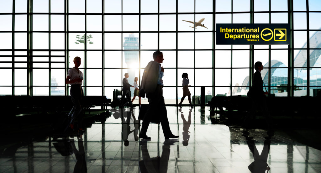 Silhouette of people walking through an international departures section of an airport