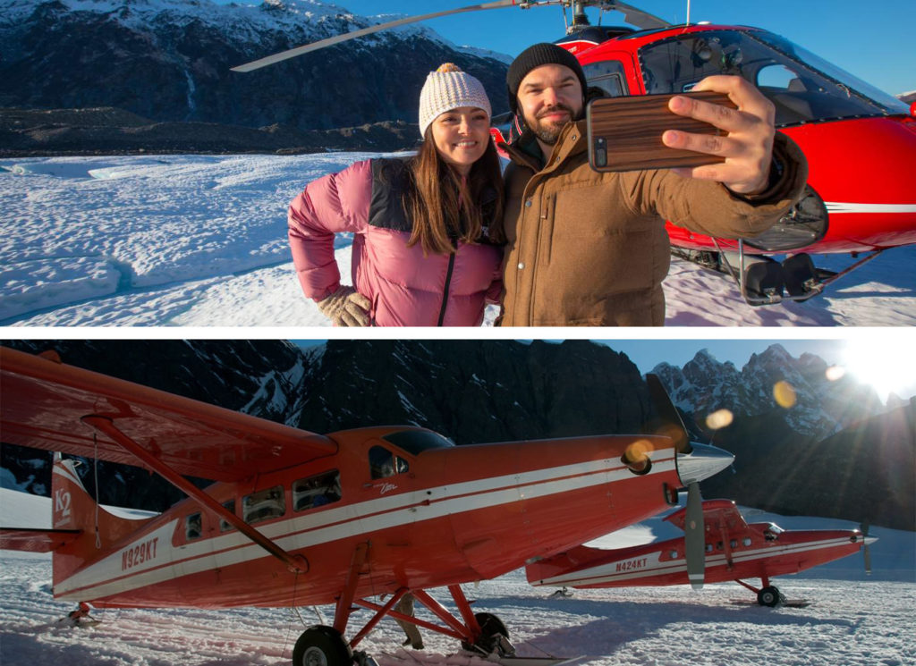 Two people dressed in winter clothes taking a selfie in front of a red helicopter (top) and a small red plane on a snowy field (bottom)