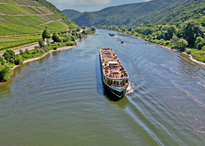 Aerial view of a Uniworld River Cruises ship passing through a river valley