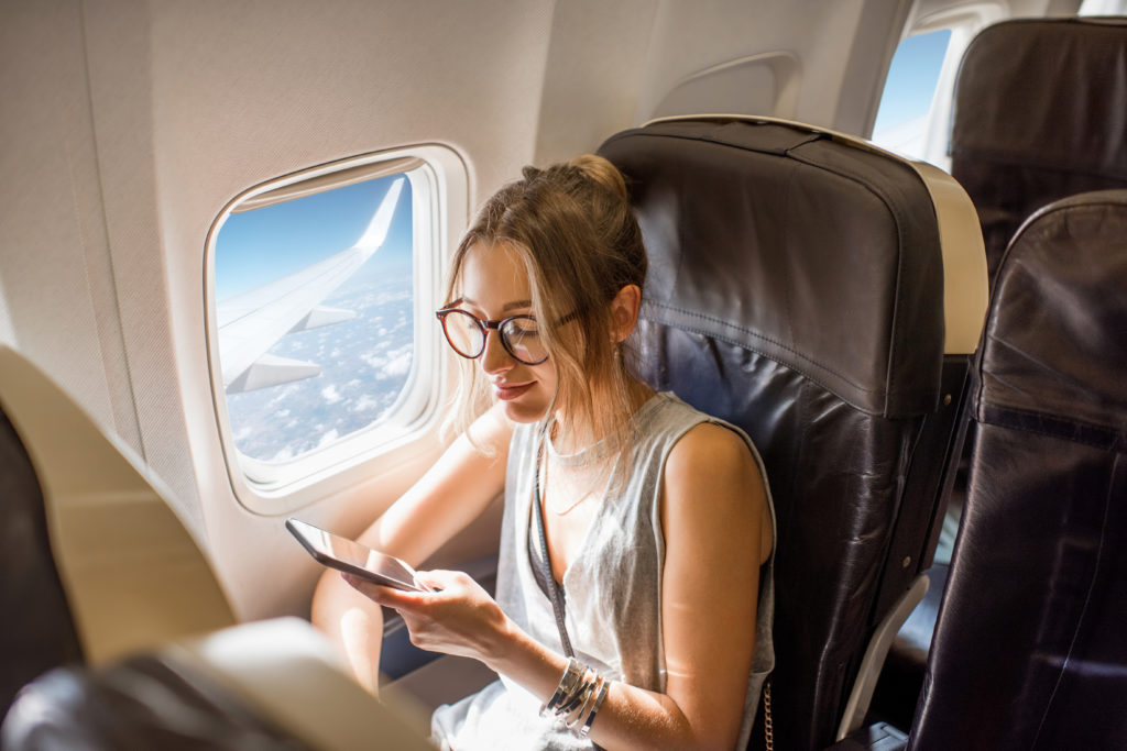 High angle view of woman using her cellphone on an airplane