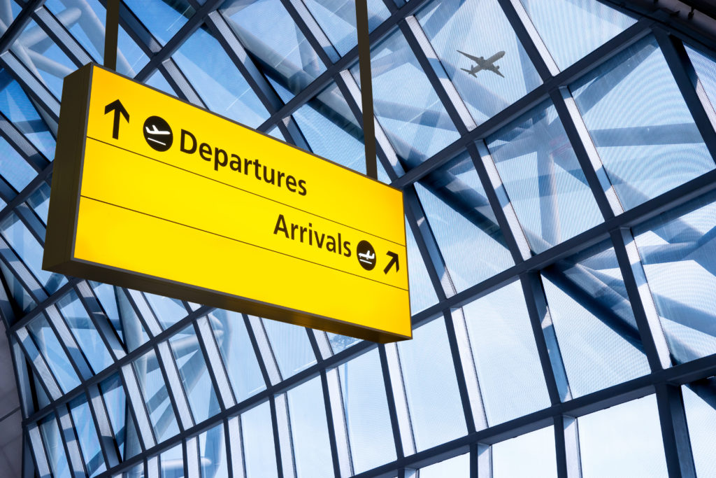 Departures and Arrivals sign in front of a giant window at an airport