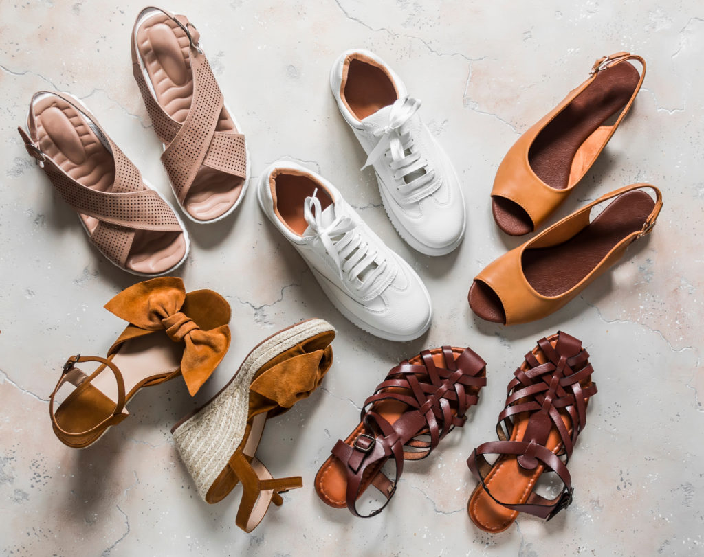 Aerial view of various sneakers and sandals in various shades of warm brown and white