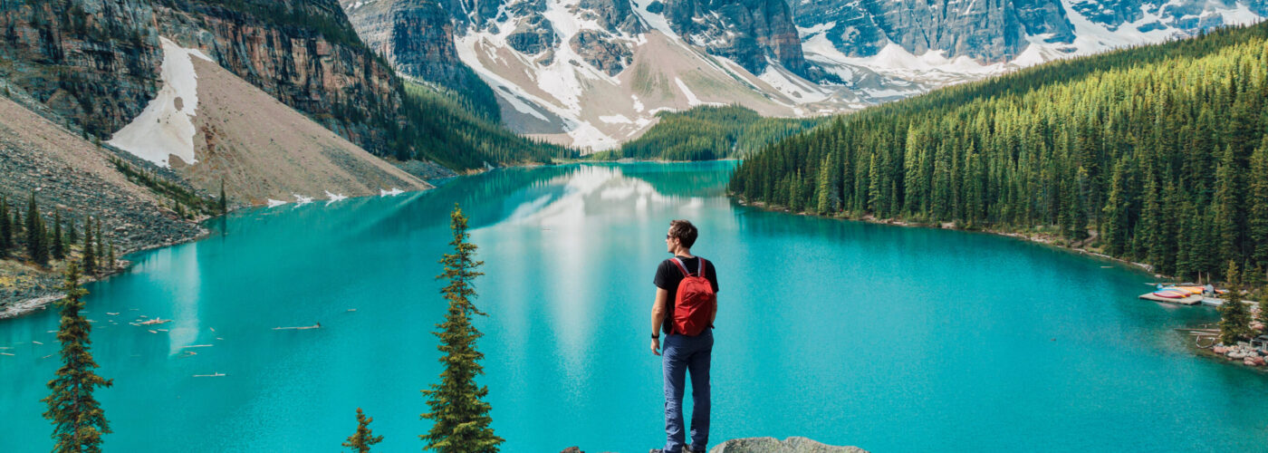 Person standing, overlooking Moraine Lake and surrounding mountains in Banff, National Park