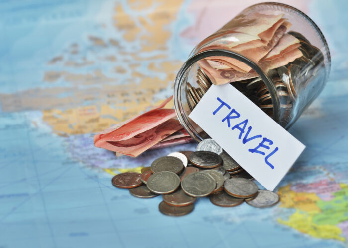 Jar of cash and coins tipped over on a world map with a label that says "travel"